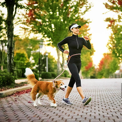 femme court joyeusement avec son chien attache a une laisse main libre chien dans un parc