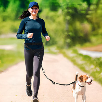 femme en tenue sportive courant en nature avec un chien attache par une laisse canicross noire fixee a la taille